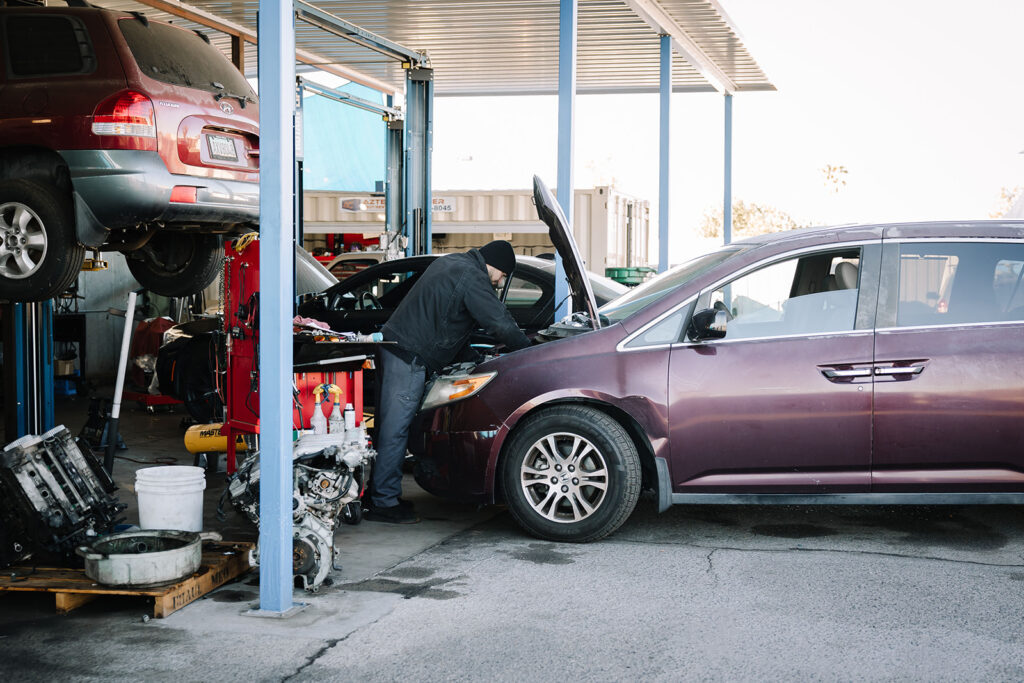 mechanic looking under the hood of a minivan